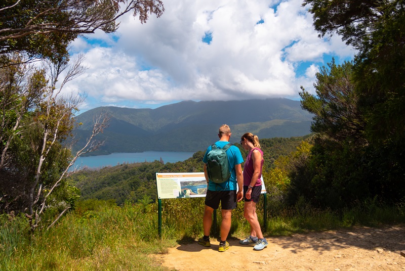 Couple looking at information board with views of water