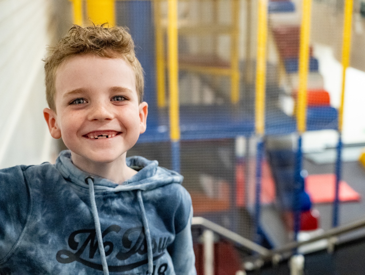 Boy with a big smiling in front of a play area